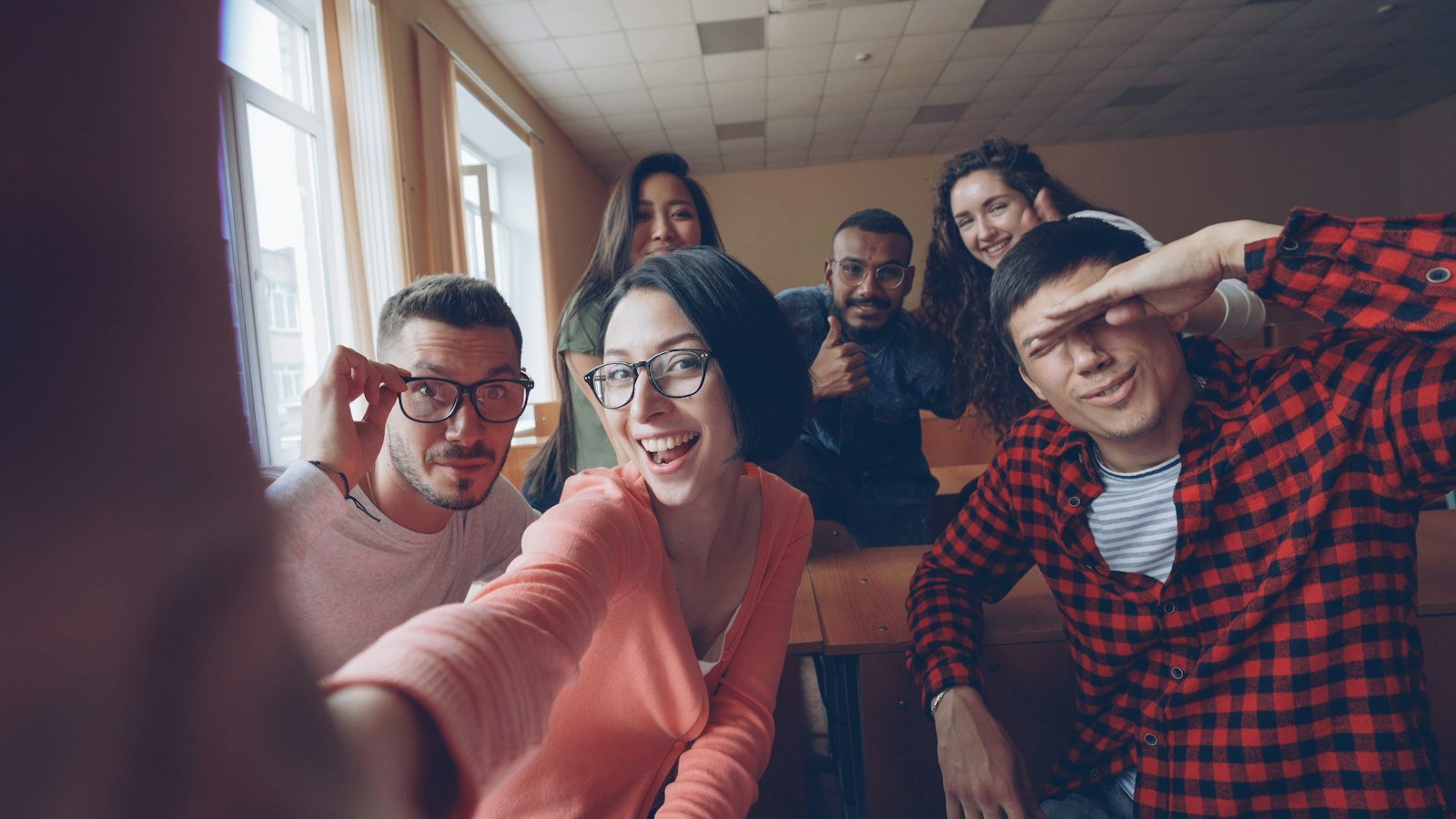 Smiling multicultural group of young people taking a selfie while practising English speaking together